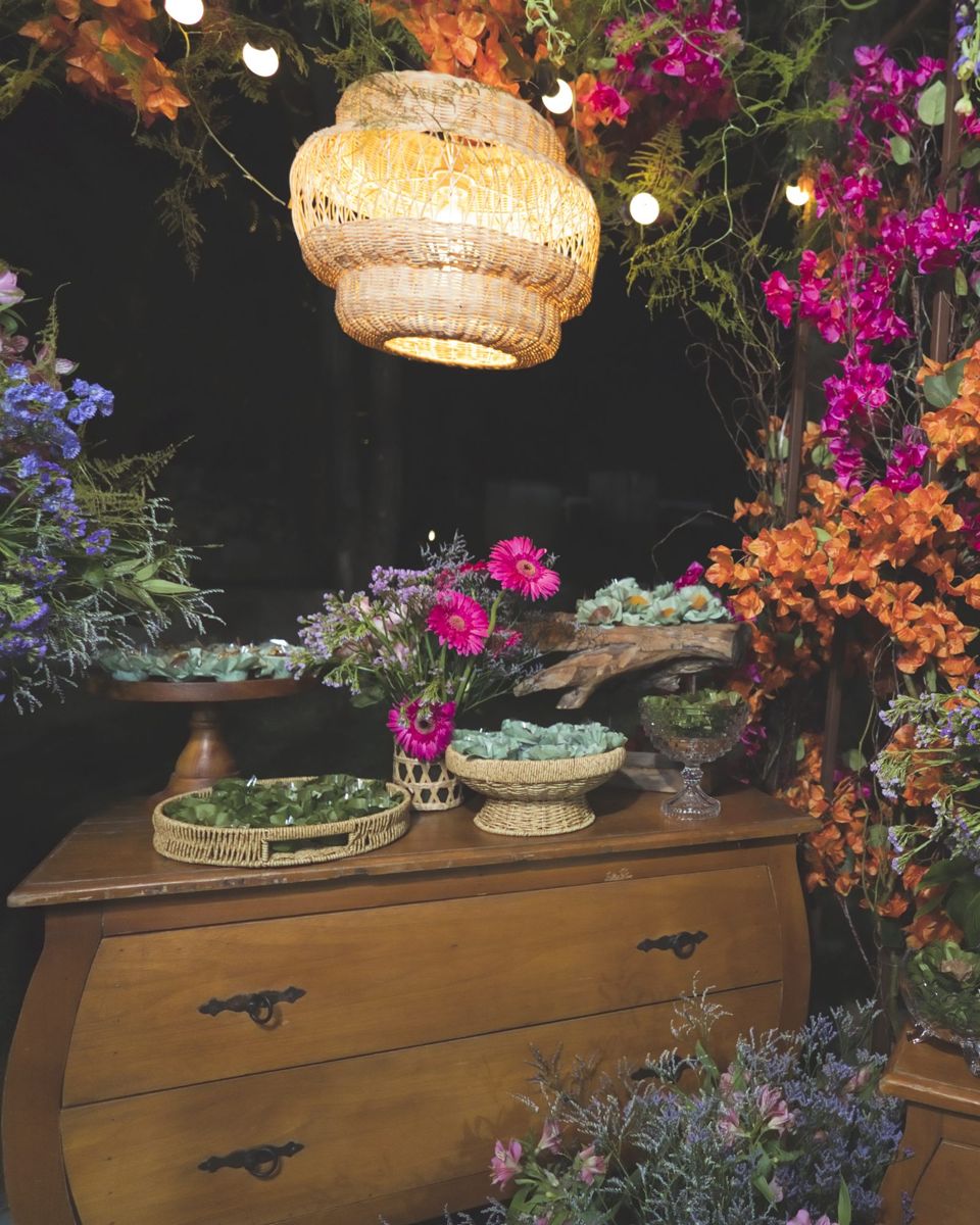 Mesa de doces com flores e luminária de palha num evento do Buffet Anciã
