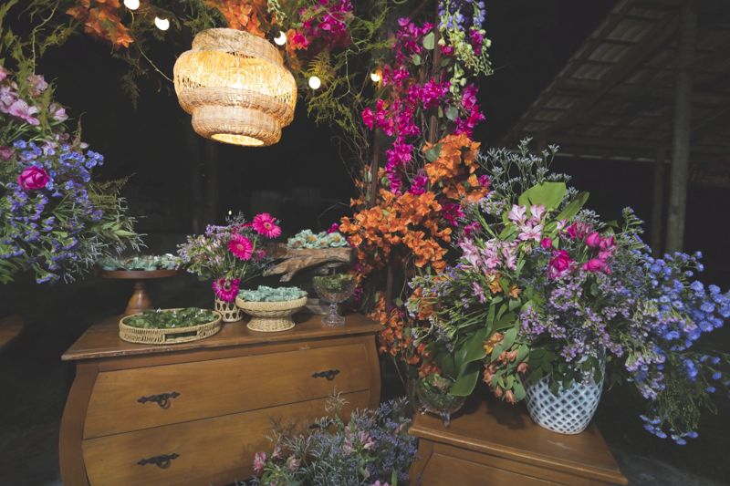 Mesa de doces com flores e luminárias de palha