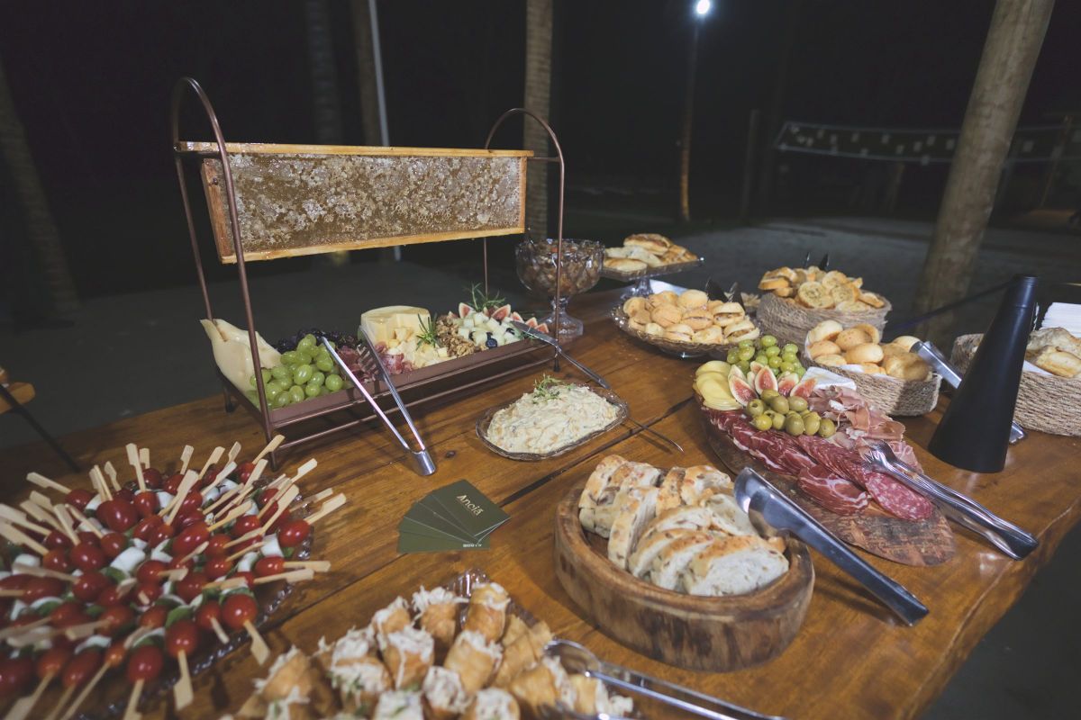Mesa de frios com favo de mel, pães, queijos e espetinhos de tomate e muçarela